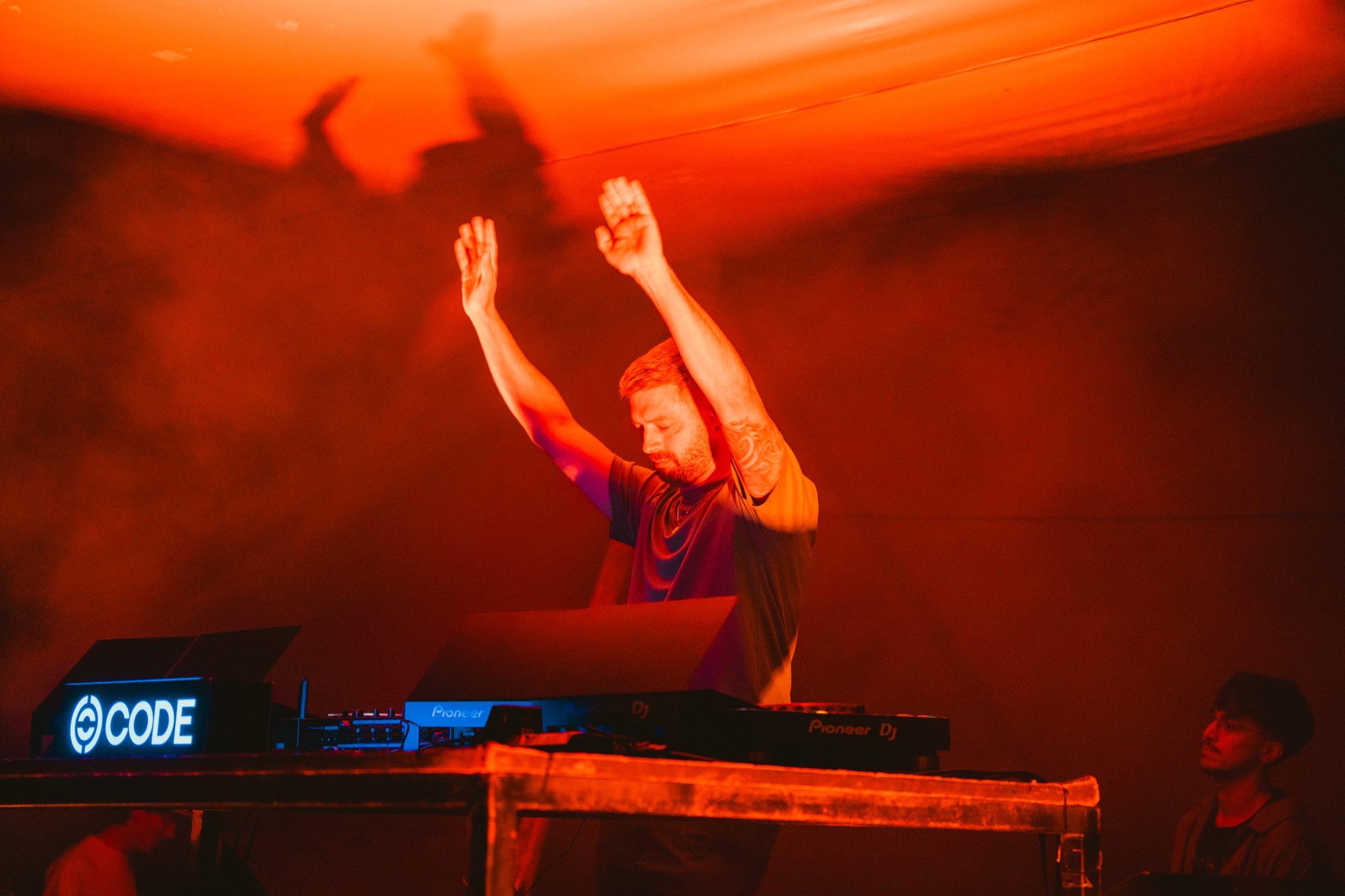 Nico Cassou con los brazos en alto detrás de los CDJ en CODE